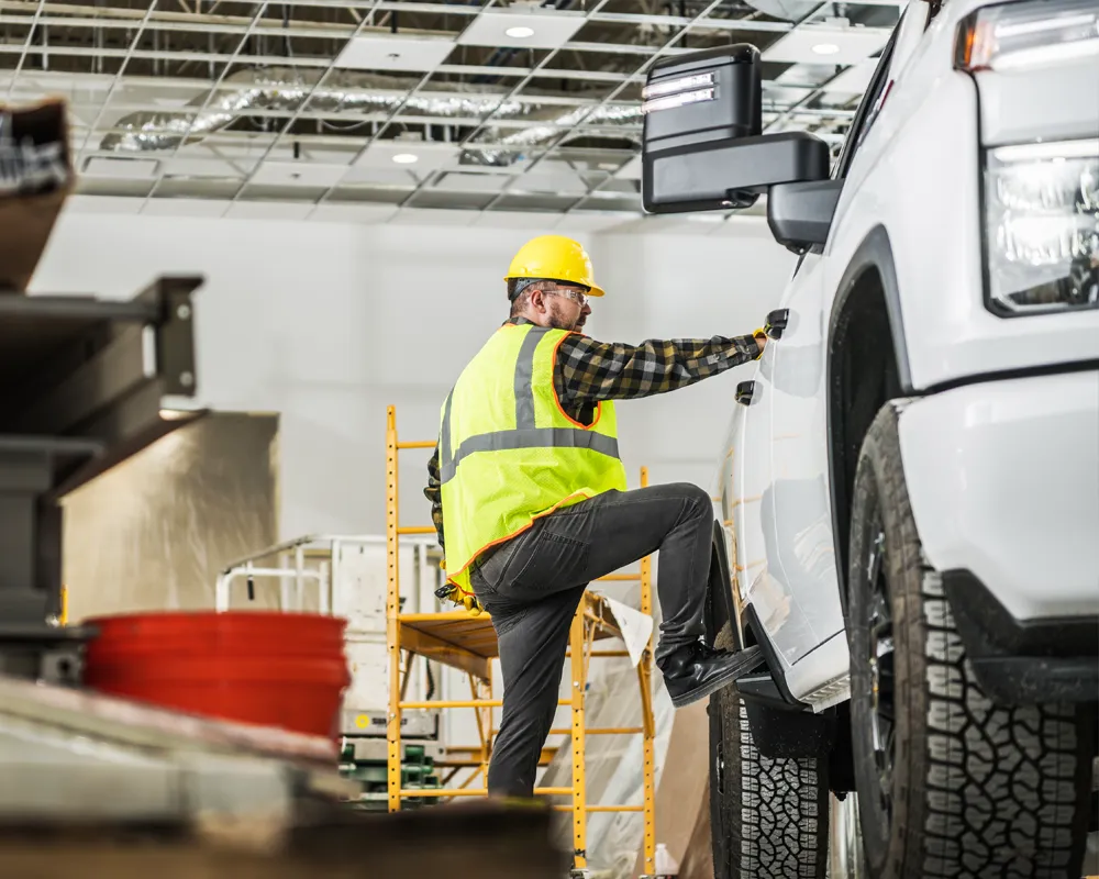 Mechanic in safety vest inspecting white truck