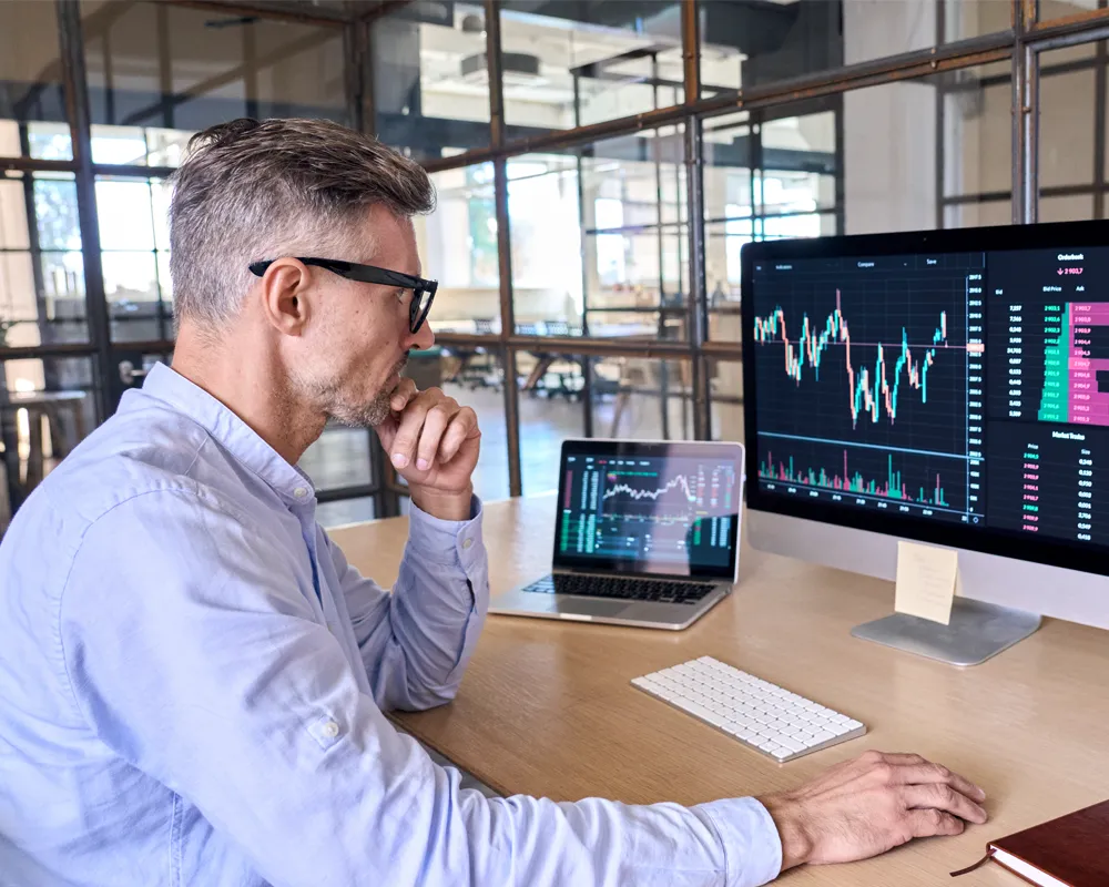 Man analyzing stock market data on multiple screens