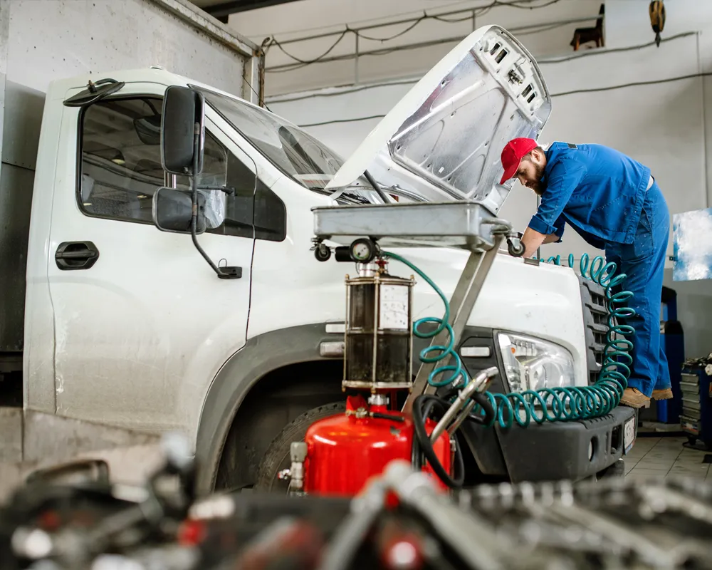 Mechanic repairing engine of white truck in garage